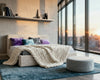 #O2 Bed Helium Cloud in a modern bedroom with a city view, featuring purple and teal throw pillows and a chunky knit blanket
